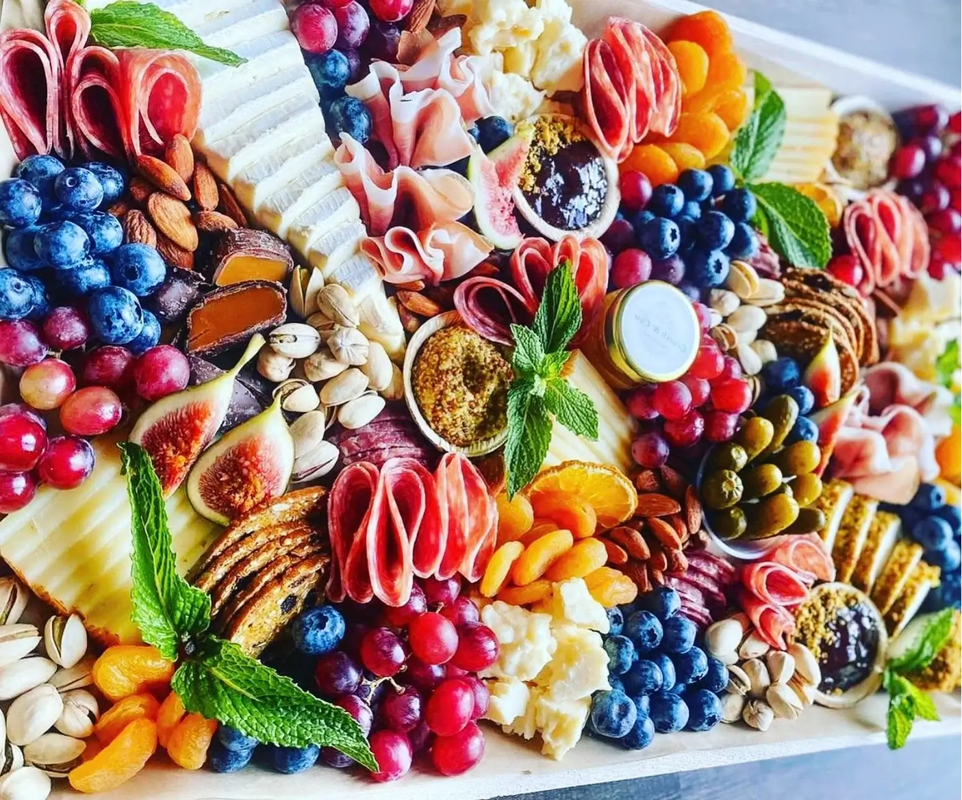 Shawna Cheese boards The Grand Graze charcuterie grazing table with assorted meats, cheeses, fruits and décor